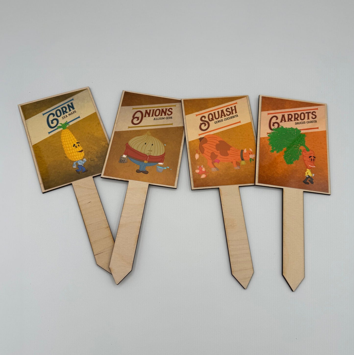 Image of Corn guy, Onion man, Squash Cow pooping seeds, Carrot Dude. Each has their vegetable name and their latin vegetable name. Example: Yea Mays for Corn.