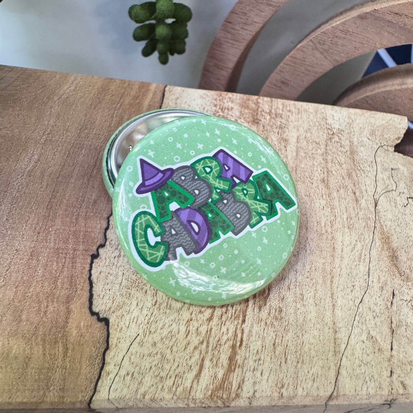 Round green badge with purple and gray design on a wooden surface
