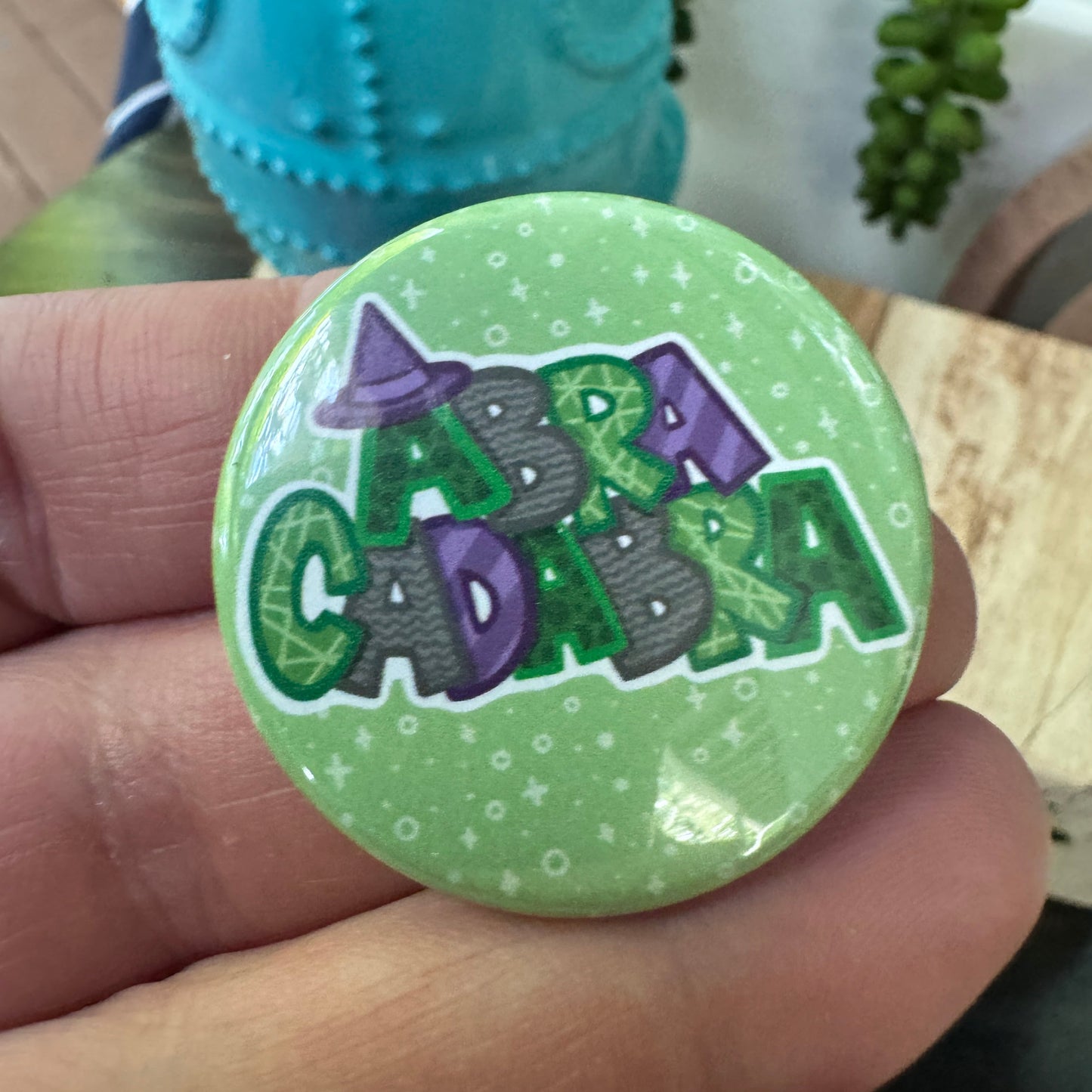 Circular green badge with purple gray and green text held by a hand, over decorative items.