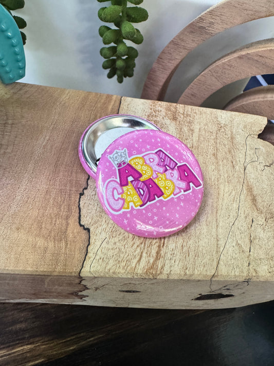 Pink button with yellow and pink text on a wooden surface